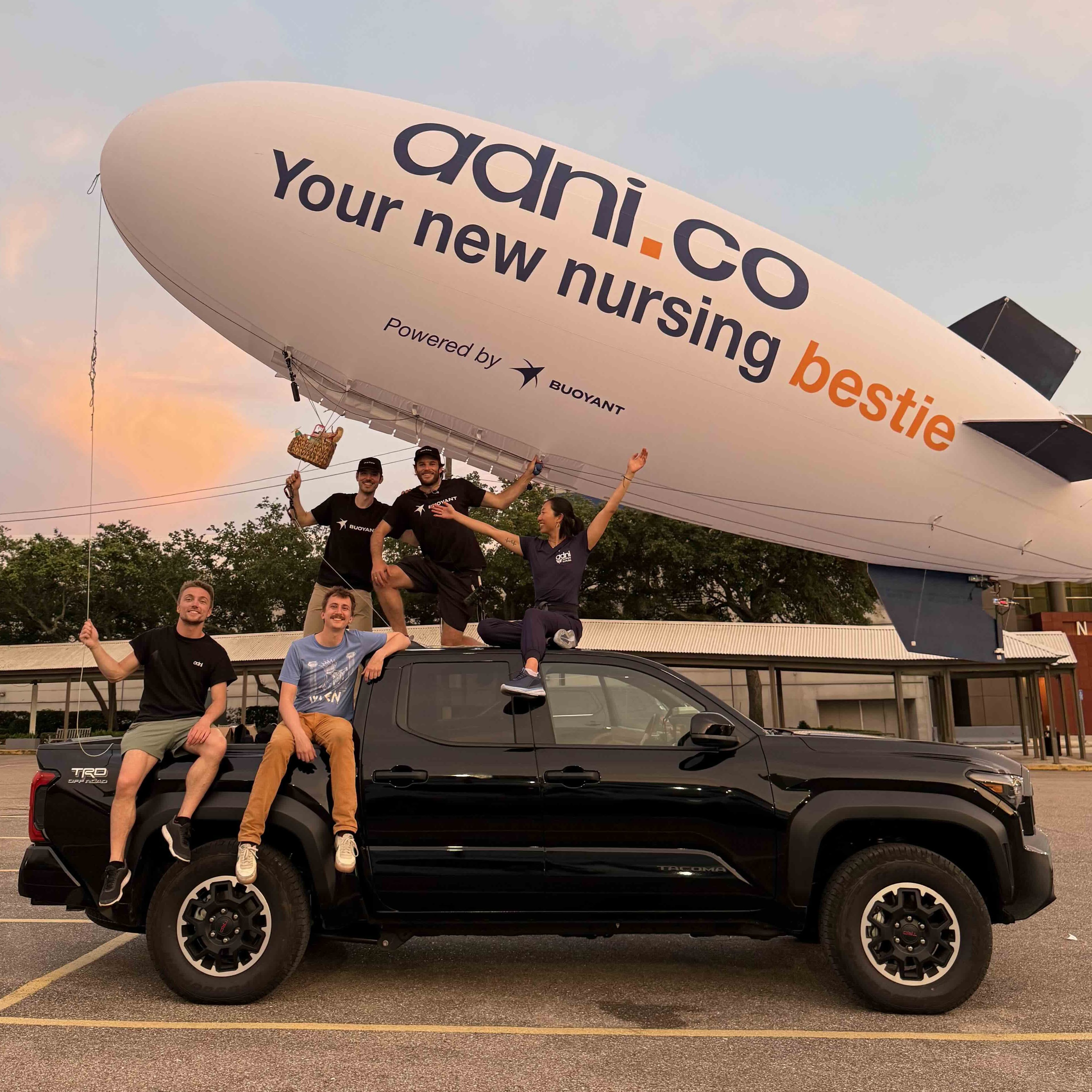 Buoyant Aero team posing with their truck and blimp displaying client branding